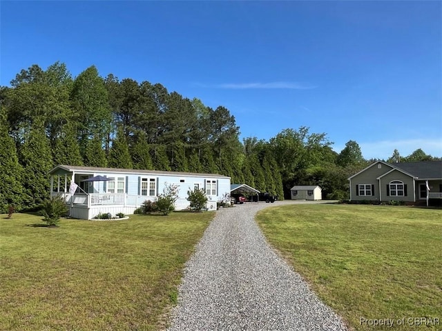 manufactured / mobile home featuring driveway, a shed, a detached carport, and a front lawn