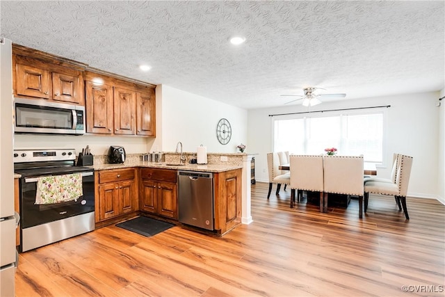 4721 Red Coach Ln, Sandston, VA 23150 - kitchen with stainless steel appliances, brown cabinets, a peninsula, a ceiling fan, and light wood-style flooring