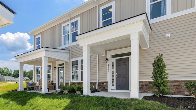 entrance to property featuring covered porch, board and batten siding, and stone siding