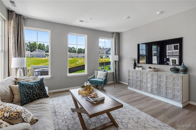 living area featuring baseboards, wood finished floors, and visible vents