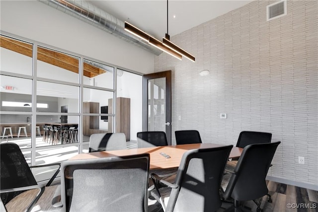 home office with visible vents, a towering ceiling, and wood finished floors