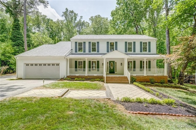 colonial inspired home featuring a garage, a front yard, a porch, and aphalt driveway