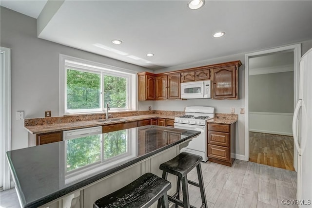 kitchen with white appliances, recessed lighting, a sink, and a kitchen bar