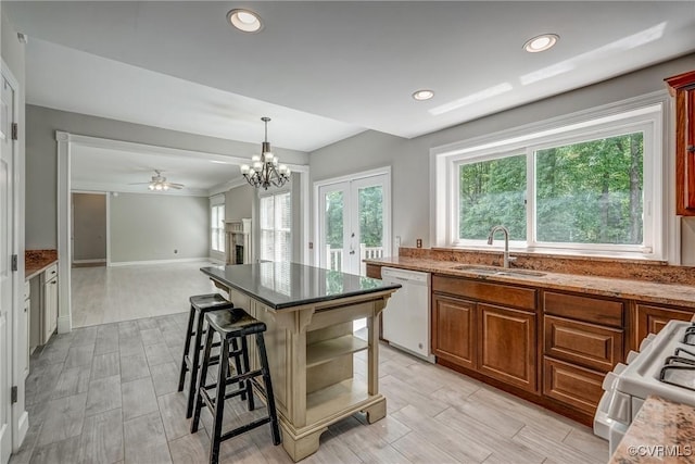 kitchen with white appliances, open floor plan, a kitchen breakfast bar, a sink, and ceiling fan with notable chandelier