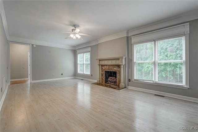 unfurnished living room with crown molding, ceiling fan, a premium fireplace, wood finished floors, and visible vents
