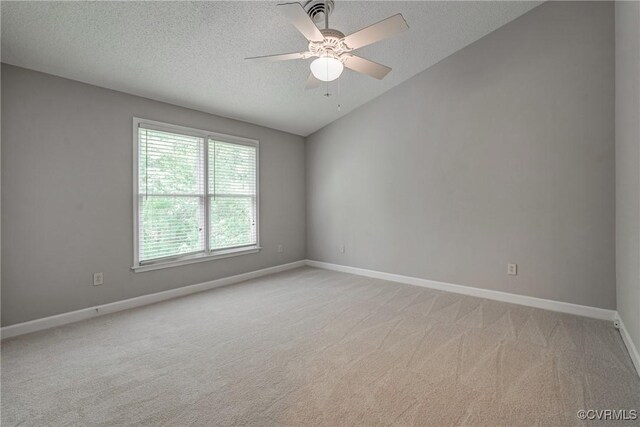 spare room with ceiling fan, light colored carpet, a textured ceiling, baseboards, and vaulted ceiling