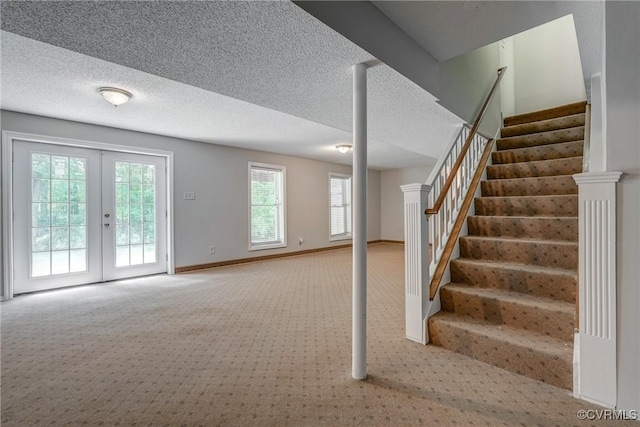 interior space with a textured ceiling, baseboards, a healthy amount of sunlight, and carpet