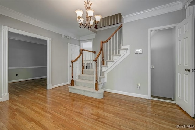 stairway featuring crown molding, baseboards, an inviting chandelier, and wood finished floors