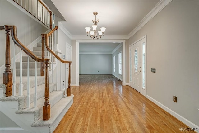foyer featuring stairway, ornamental molding, wood finished floors, and a notable chandelier