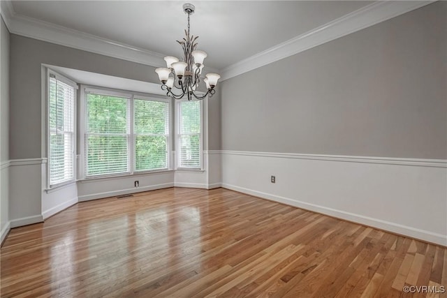spare room with baseboards, a chandelier, ornamental molding, and wood finished floors