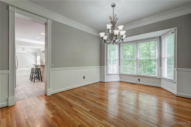 unfurnished dining area with baseboards, ornamental molding, wood finished floors, and a notable chandelier