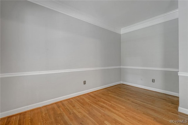 empty room featuring baseboards, ornamental molding, and light wood-type flooring
