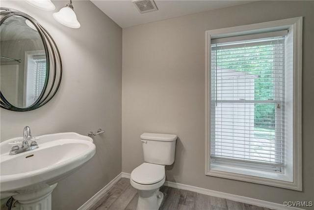 half bathroom featuring a sink, toilet, baseboards, wood finished floors, and visible vents