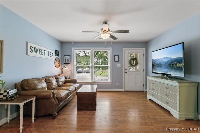living room featuring baseboards, a ceiling fan, and wood finished floors