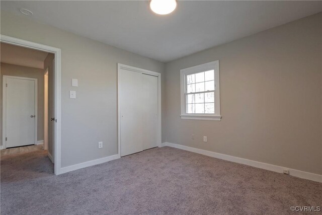 unfurnished bedroom with baseboards, carpet, and a closet