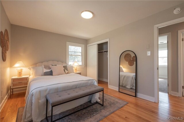 bedroom with light wood-style floors, baseboards, and a closet