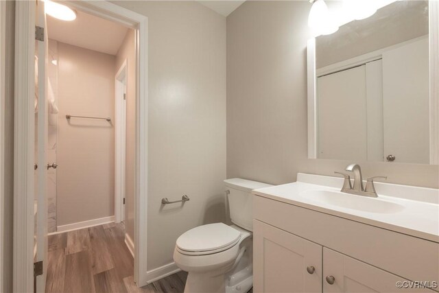 bathroom featuring vanity, baseboards, toilet, and wood finished floors