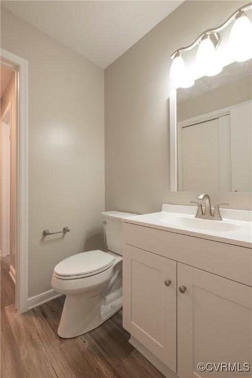 bathroom with vanity, baseboards, toilet, and wood finished floors