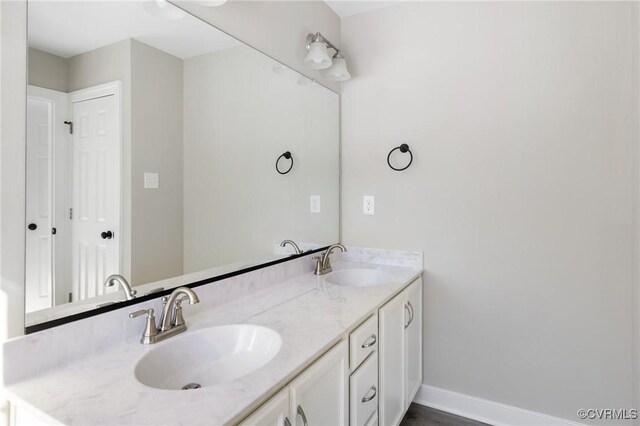 bathroom featuring double vanity, baseboards, and a sink