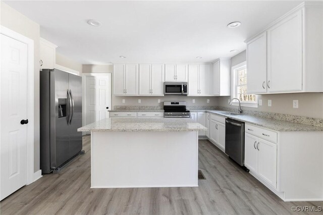 kitchen with white cabinets, stainless steel appliances, a sink, and light wood-style flooring