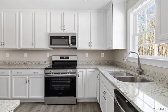 kitchen featuring a sink, light wood-style floors, stainless steel appliances, and white cabinetry