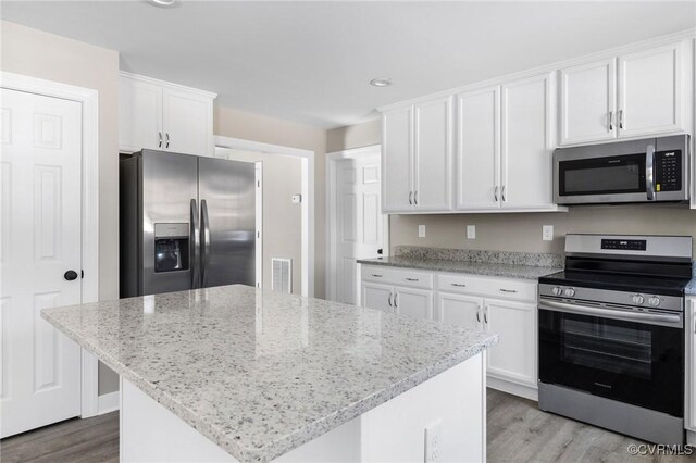 kitchen with light stone counters, stainless steel appliances, light wood finished floors, and white cabinetry