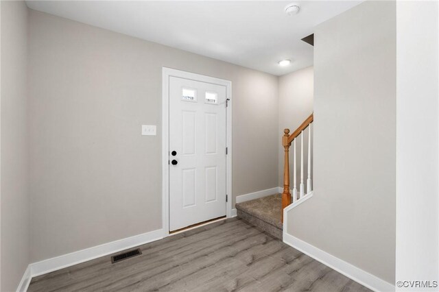 entrance foyer featuring baseboards, visible vents, wood finished floors, and stairway
