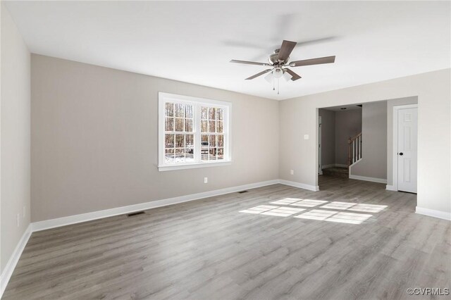 spare room with ceiling fan, visible vents, wood finished floors, stairway, and baseboards