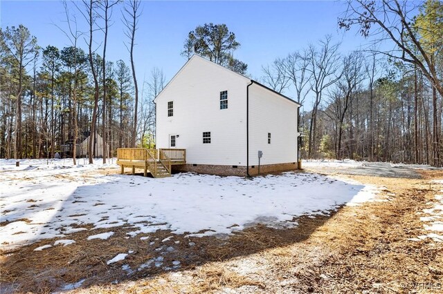 snow covered property featuring a wooden deck and crawl space
