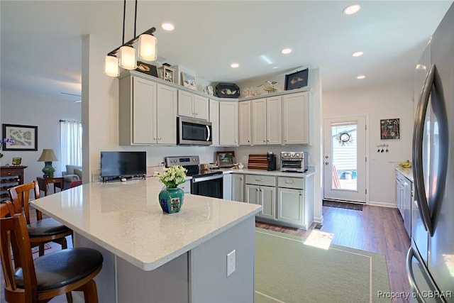 1676 Windsor Rd, Dutton, VA 23050 - kitchen with appliances with stainless steel finishes, a peninsula, a breakfast bar, wood finished floors, and hanging light fixtures