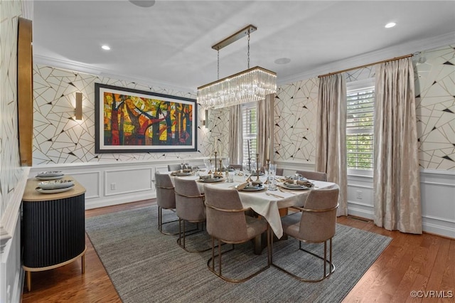 dining room featuring ornamental molding, a decorative wall, and wood finished floors