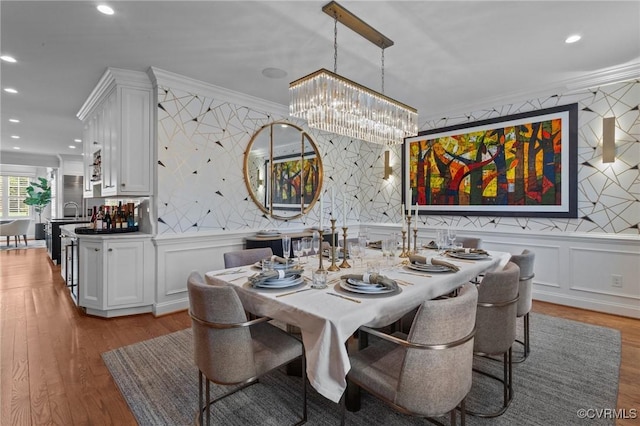 dining room featuring ornamental molding, recessed lighting, wood finished floors, and a notable chandelier