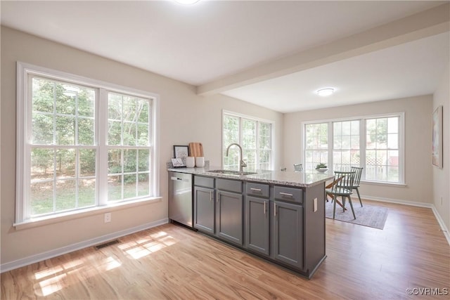 kitchen featuring stainless steel dishwasher, baseboards, a sink, and light wood finished floors