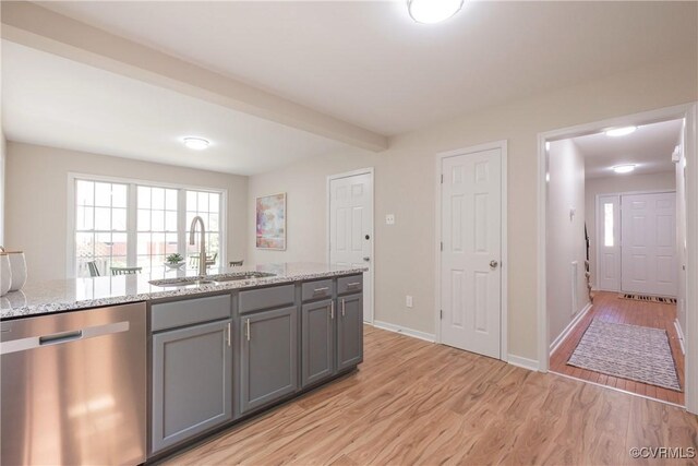 kitchen featuring light stone countertops, a sink, light wood-style flooring, stainless steel dishwasher, and gray cabinetry