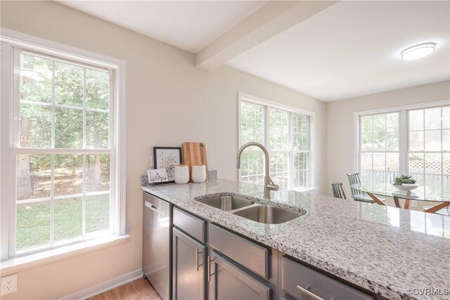 kitchen with a sink, light stone counters, gray cabinets, and dishwasher