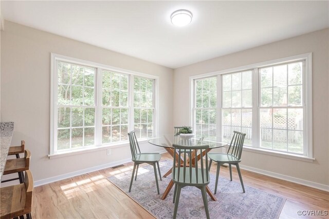 dining space with baseboards, plenty of natural light, light wood-type flooring, and visible vents