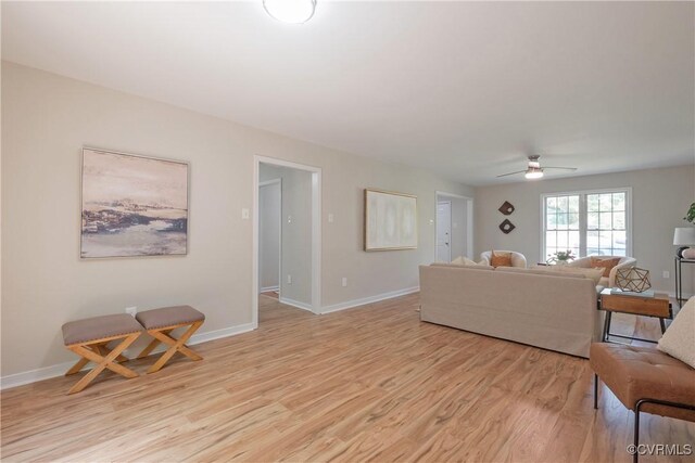living room featuring baseboards, light wood finished floors, and ceiling fan