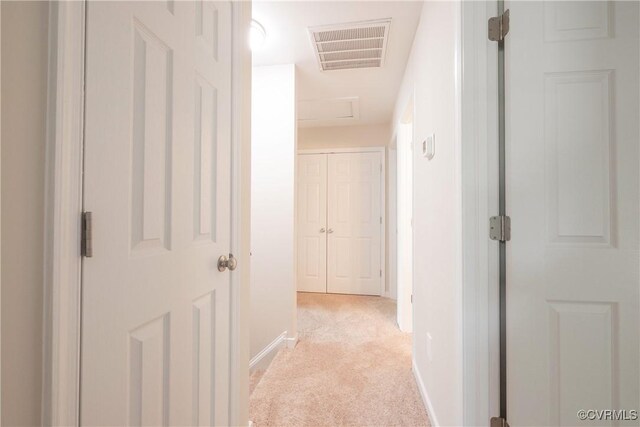 hall featuring baseboards, light colored carpet, attic access, and visible vents