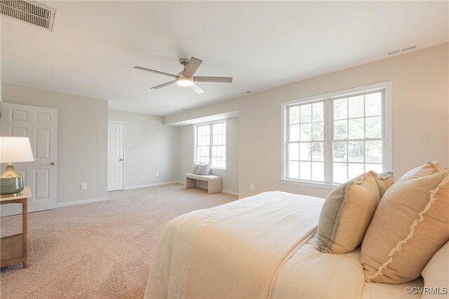 bedroom with visible vents, baseboards, ceiling fan, and light carpet