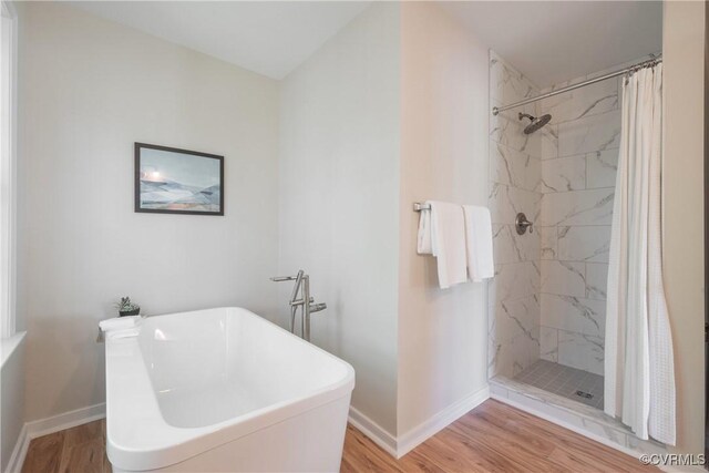 full bath with a soaking tub, baseboards, and wood finished floors