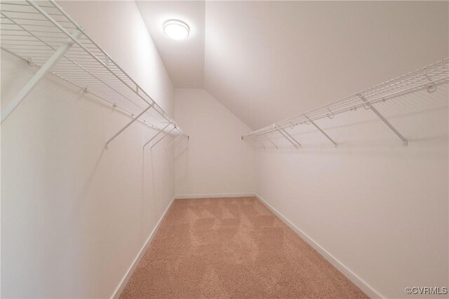 spacious closet with light carpet and vaulted ceiling