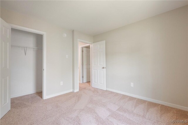 unfurnished bedroom with baseboards, light carpet, and a closet