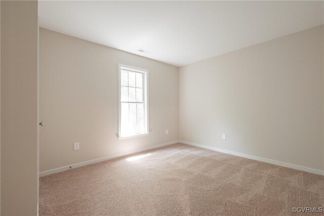 spare room with baseboards and light colored carpet
