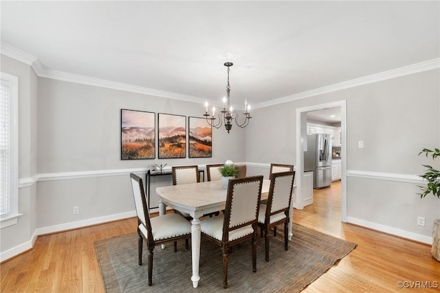 dining space featuring light wood-style floors, baseboards, crown molding, and a notable chandelier