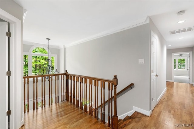 hallway featuring baseboards, an upstairs landing, wood finished floors, and visible vents