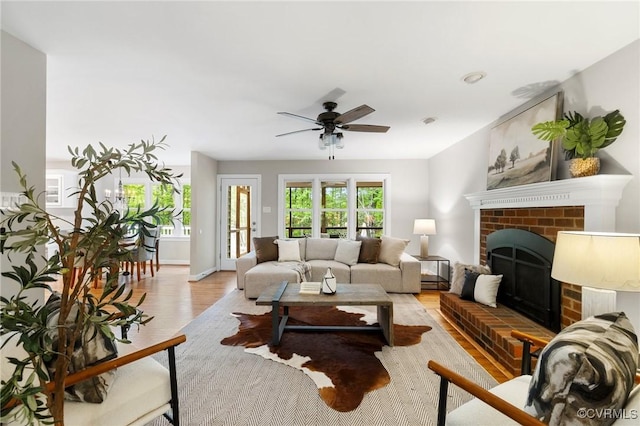 living room featuring ceiling fan, wood finished floors, and a fireplace