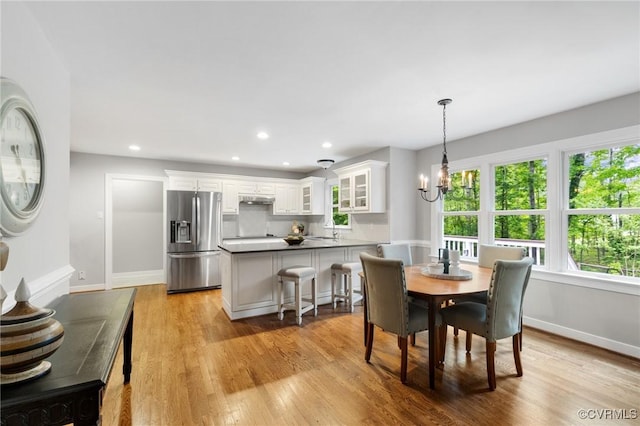 dining space with baseboards, recessed lighting, light wood-style flooring, and an inviting chandelier