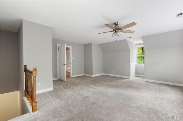 carpeted empty room featuring ceiling fan, visible vents, baseboards, and vaulted ceiling