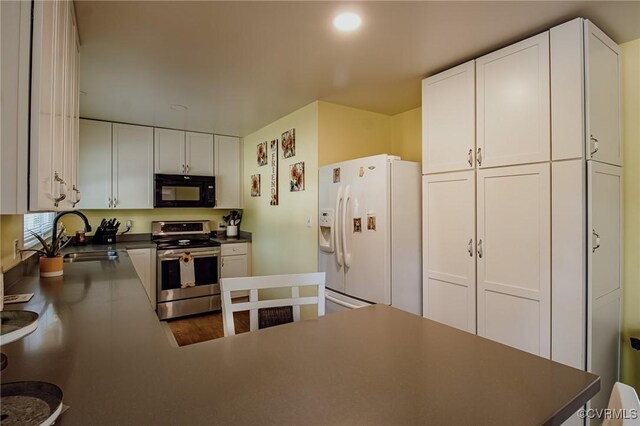 kitchen featuring electric range, black microwave, a sink, white cabinets, and white fridge with ice dispenser