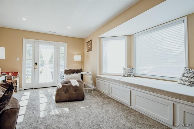 living area featuring baseboards, light carpet, and visible vents